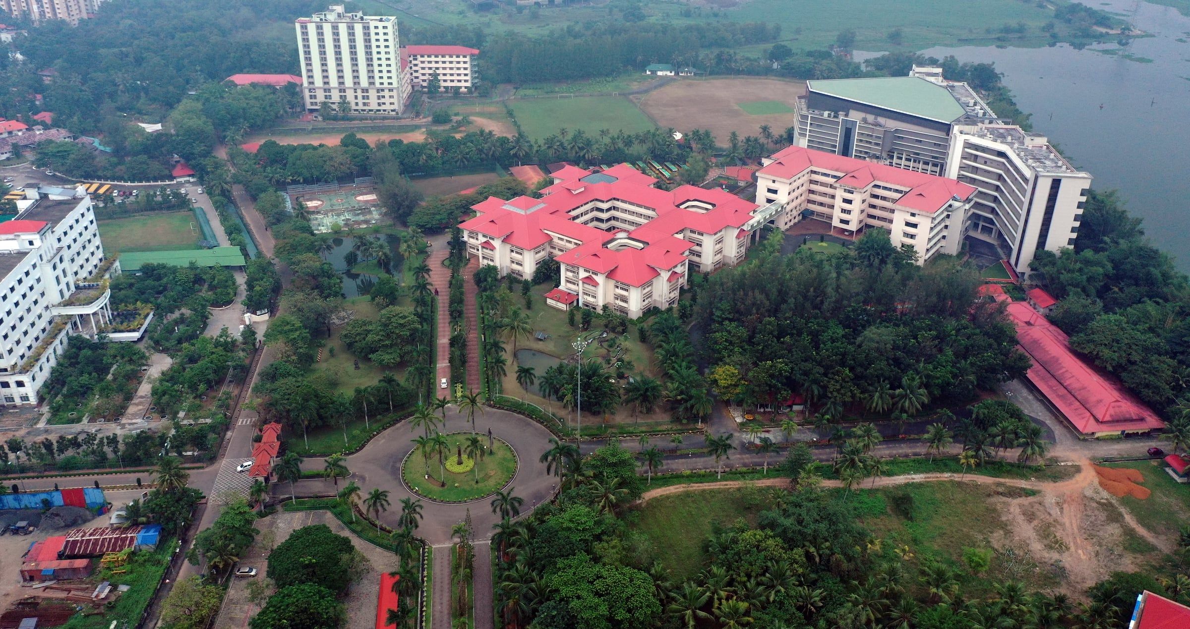 Aerial view of the Rajagiri Valley campus in Kakkanad: red-roofed academic blocks, palm-lined drive and the backwaters beyond