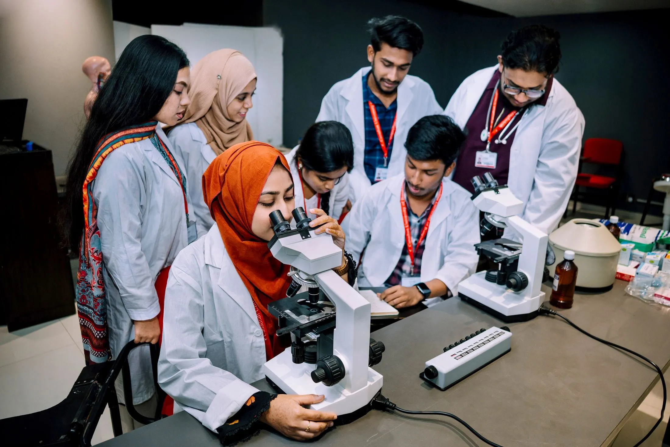 Students in lab coats at microscopes