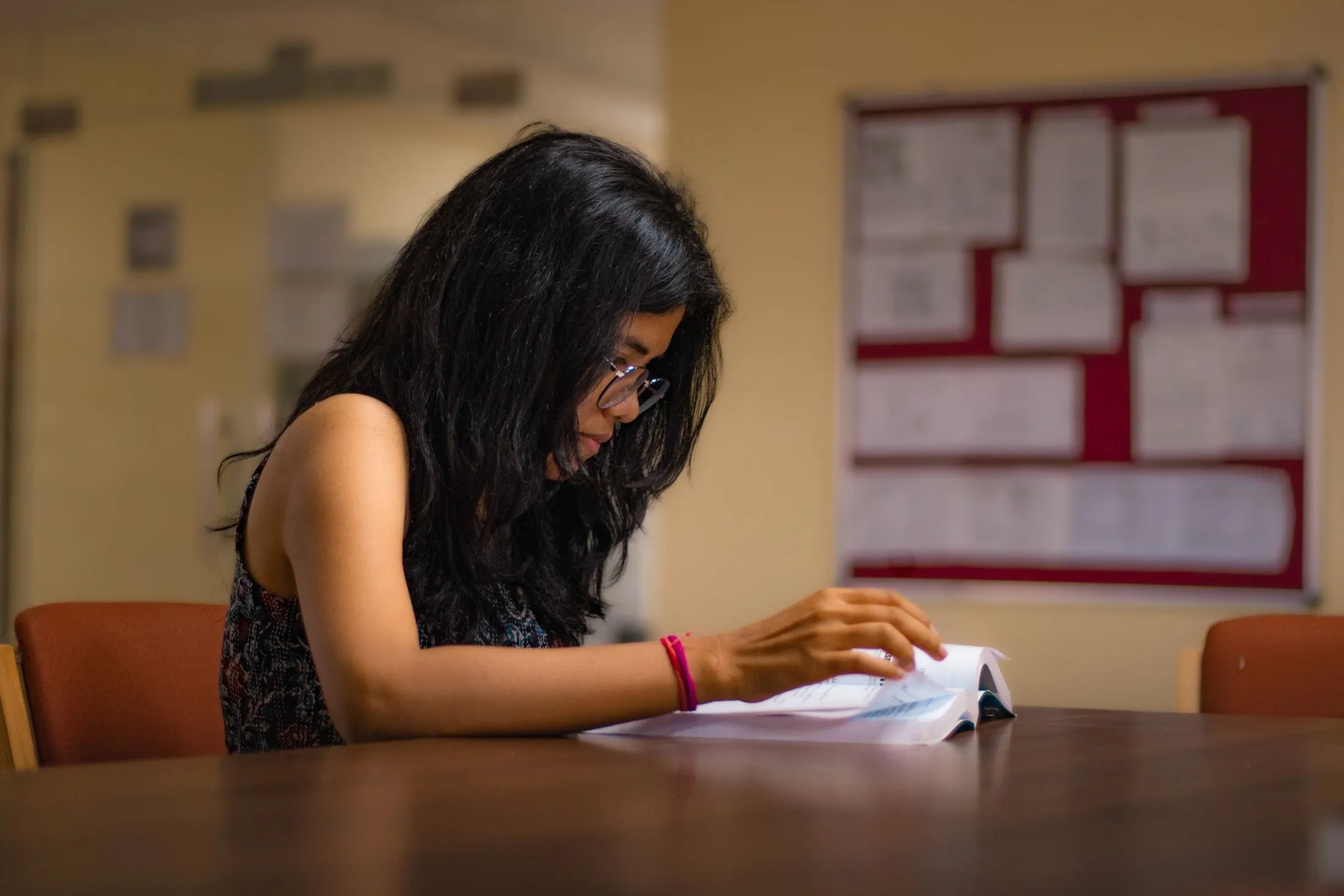 Student reading a textbook at a library desk